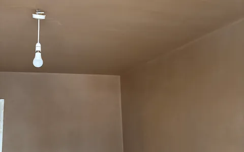 Freshly skimmed walls and ceiling in an empty room, with a bare bulb hanging from the ceiling